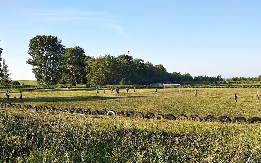 Campo de futebol de bairro com jogadores ao longe
